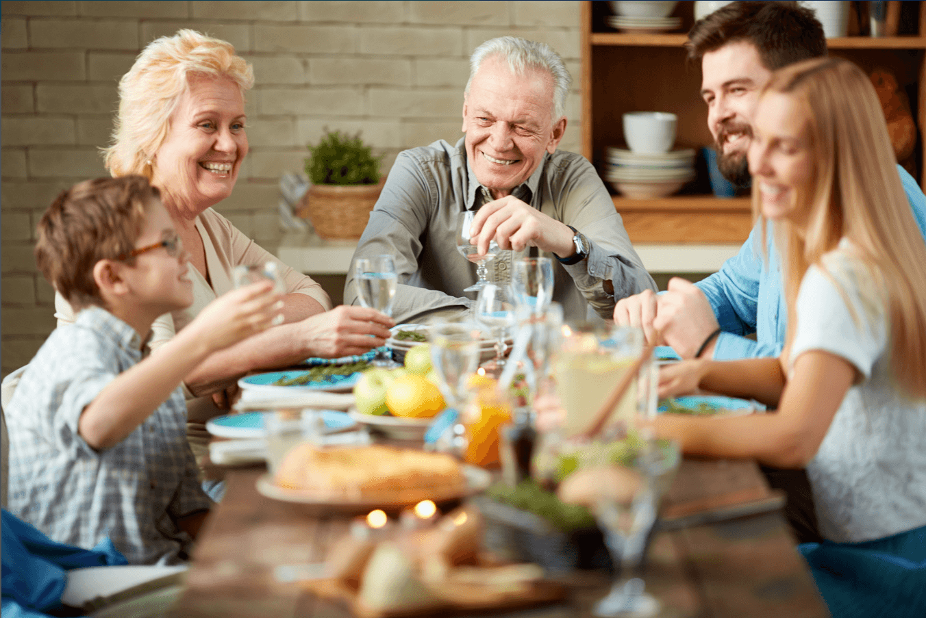 A multigenerational family shares a warm dinner together (grandparents, parents, and children), representing the Sandwich Generation's everyday balancing act.